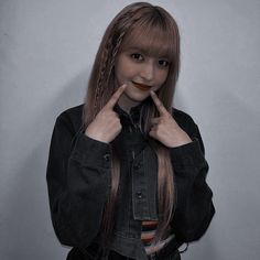 a girl with long hair and braids posing for the camera in front of a gray background