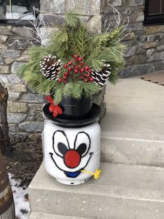 a potted plant with a clown face painted on it and pine cones in the background