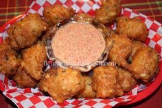 some fried food on a red and white checkered plate with dipping sauce in the middle