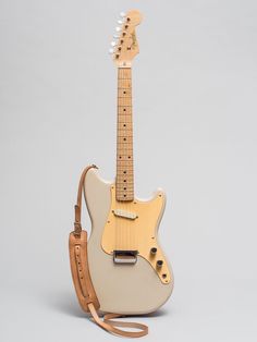 an electric guitar sitting on top of a white table next to a brown leather bag