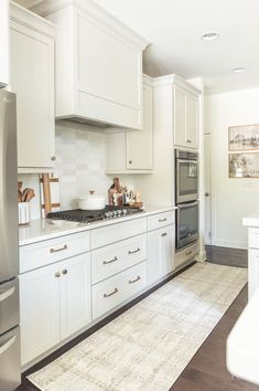 a kitchen with white cabinets and stainless steel appliances