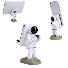 an astronaut figurine holding a cell phone next to another figure in front of a computer monitor