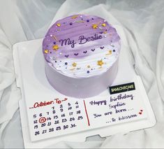 a purple birthday cake sitting on top of a calendar