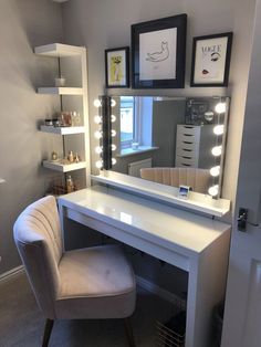 a white vanity with lights on it and a chair in front of the mirror that is lit up