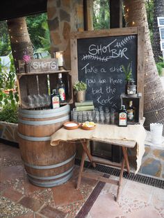 a wooden barrel sitting in front of a chalkboard with writing on it next to a table