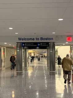 people are walking through an airport terminal with their suitcases in hand and the sign welcome to boston above them