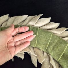 a hand holding a ring on top of a piece of cloth next to a green leaf