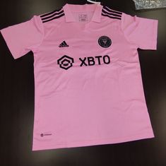 a pink shirt with black and white letters on the chest, sitting on a table