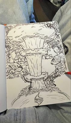 an open book with a drawing of a tree on the front and back cover, in someone's lap