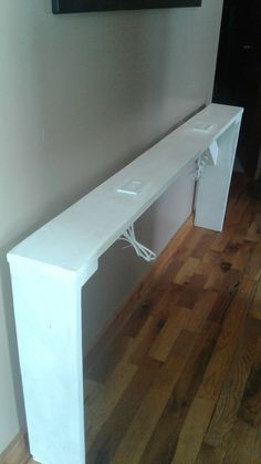 a white bench sitting on top of a hard wood floor next to a framed painting