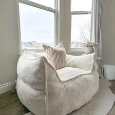 a large white bean bag chair sitting in front of a window next to a rug