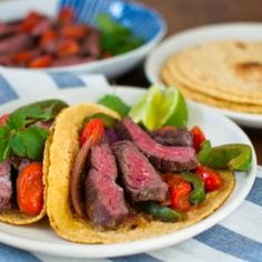 there are two tacos on the plate with meat and vegetables in it, along with other food items