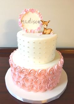 a three tiered cake decorated with pink flowers and a small deer on the top