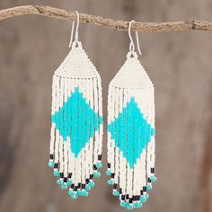 white and blue beaded earrings hanging from a tree branch