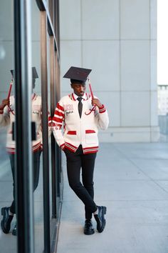 a man in a graduation cap and gown is leaning against a wall with his hands on his head