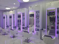 the interior of a hair salon with purple lights on the walls and chairs in front of them