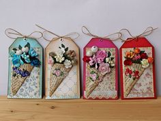 three ice cream cones decorated with flowers are hanging from twine strings on a wall