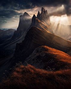 the sun shines through the clouds over some mountain peaks in the mountainside area