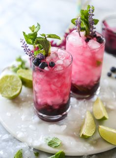 two glasses filled with blueberry lemonade and mint spritz on a white plate