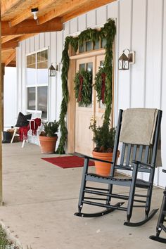 two rocking chairs on the front porch with christmas wreaths and potted greenery