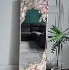 a large mirror sitting on top of a table next to a vase and potted plant