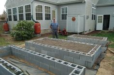 a man standing in front of a house with cinder blocks laid out on the ground