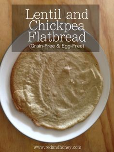 a white plate topped with a flatbread on top of a wooden table next to a cup of coffee