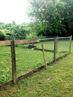 a fenced in area with grass and trees