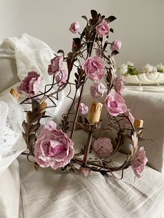 a pink flower arrangement on a bed with white linens and lace in the background