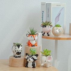 small ceramic animal planters on a wooden table next to a book and bookshelf