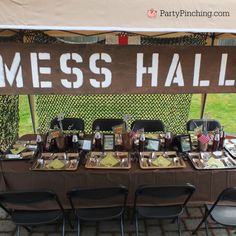 a table set up for a mess hall party with plates and cups on it, under a sign that says mess hall