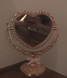 a heart shaped mirror sitting on top of a wooden table