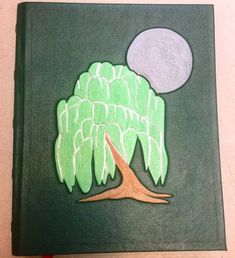 a book with an image of a tree in the middle and a moon above it