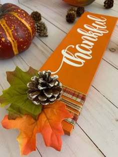 an orange sign with a pine cone and some leaves on it next to pumpkins