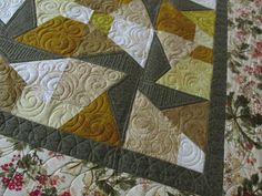 a quilted table topper with flowers and leaves on it's edges,