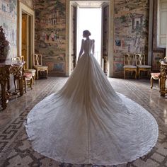 a woman in a wedding dress standing at the entrance to a room with paintings on the walls