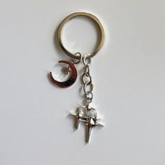 a metal keychain with an airplane and crescent charm on the end of it