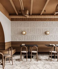 the interior of a restaurant with wooden tables and chairs in front of a wall that has letters on it