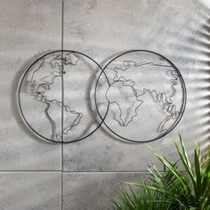 two metal circles with the earth on them are shown in front of a cement wall