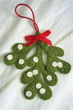 a green christmas ornament with white buttons and a red ribbon hanging from it