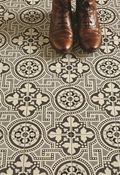 a pair of brown shoes sitting on top of a tiled floor