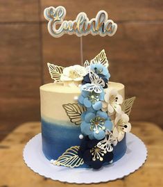 the cake is decorated with blue flowers and gold leaves on it's top tier