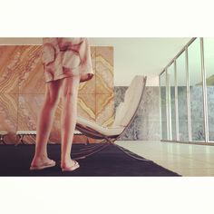 a woman standing on top of a black rug in front of a wall with glass windows