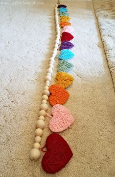 a row of crocheted hearts on the floor next to a string of yarn