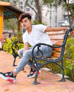 a young man sitting on top of a wooden bench