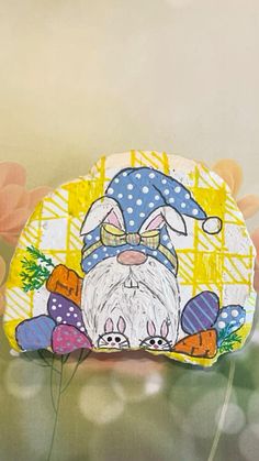 a rock painted with an image of a gnome on it's face and flowers in the background