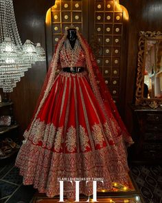 a red and gold wedding gown on display in front of a mirror with chandelier