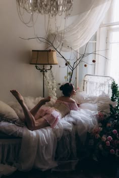 a woman laying on top of a bed next to a chandelier