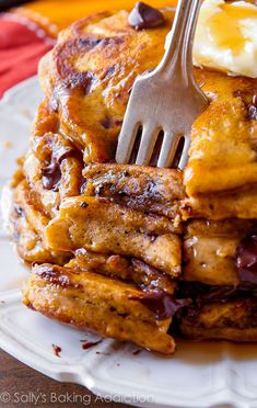 a stack of chocolate chip pancakes with butter and syrup on top is being eaten by a fork