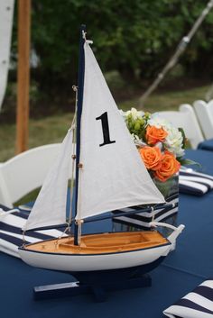 a small sailboat is sitting on a table with blue and white striped linens